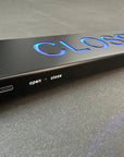 Black door handle with 'CLOSED' indicator on a gray surface