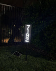 Vertical metal address plaque staked in garden bed improving home exterior design