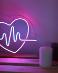 Neon sign of a heart with a pulse line on a wooden shelf with candles.