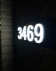 Illuminated LED house numbers at night with warm white halo lighting effect