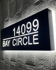 Matte black address sign with street name installed on dark exterior siding