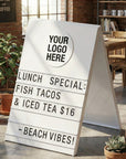 Outdoor cafe with a sandwich board displaying lunch specials and beach vibes.