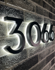 Modern backlit house numbers 3066 mounted on dark stone wall for high contrast visibility