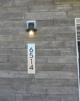 Vertical modern 3D backlit address plaque mounted on wood siding for contemporary home entry