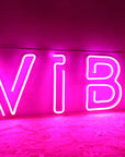 Neon sign with the word 'VIBE' on a dark background