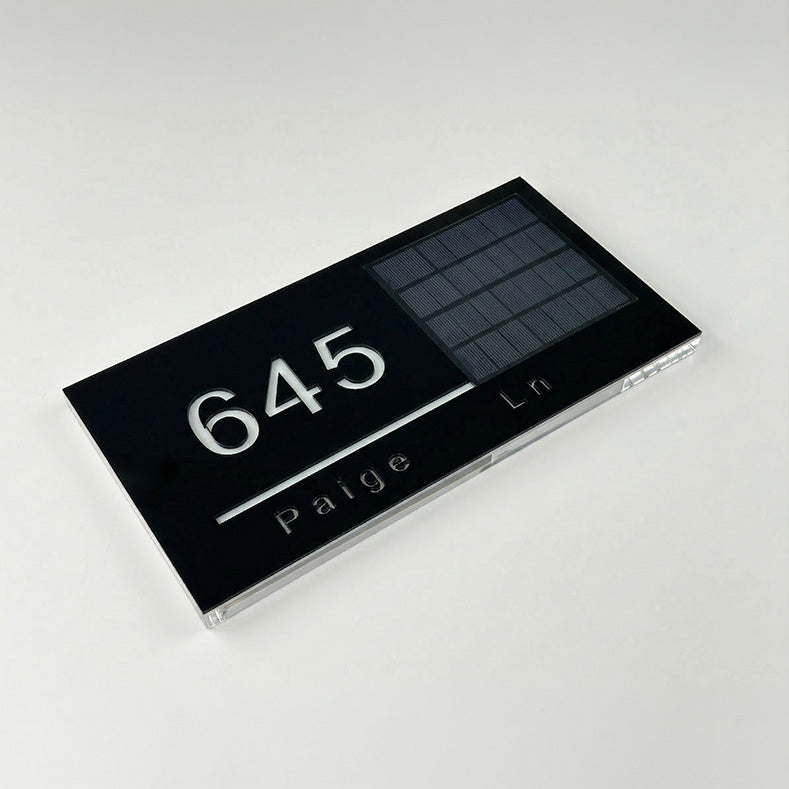 Black address sign with numbers and text on a white background