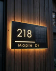 Custom solar LED address sign with illuminated house numbers and street name mounted on exterior wall