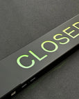 Metallic door handle with 'CLOSED' text on a black surface