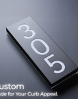 Metallic house number plaque with '305' on a dark background