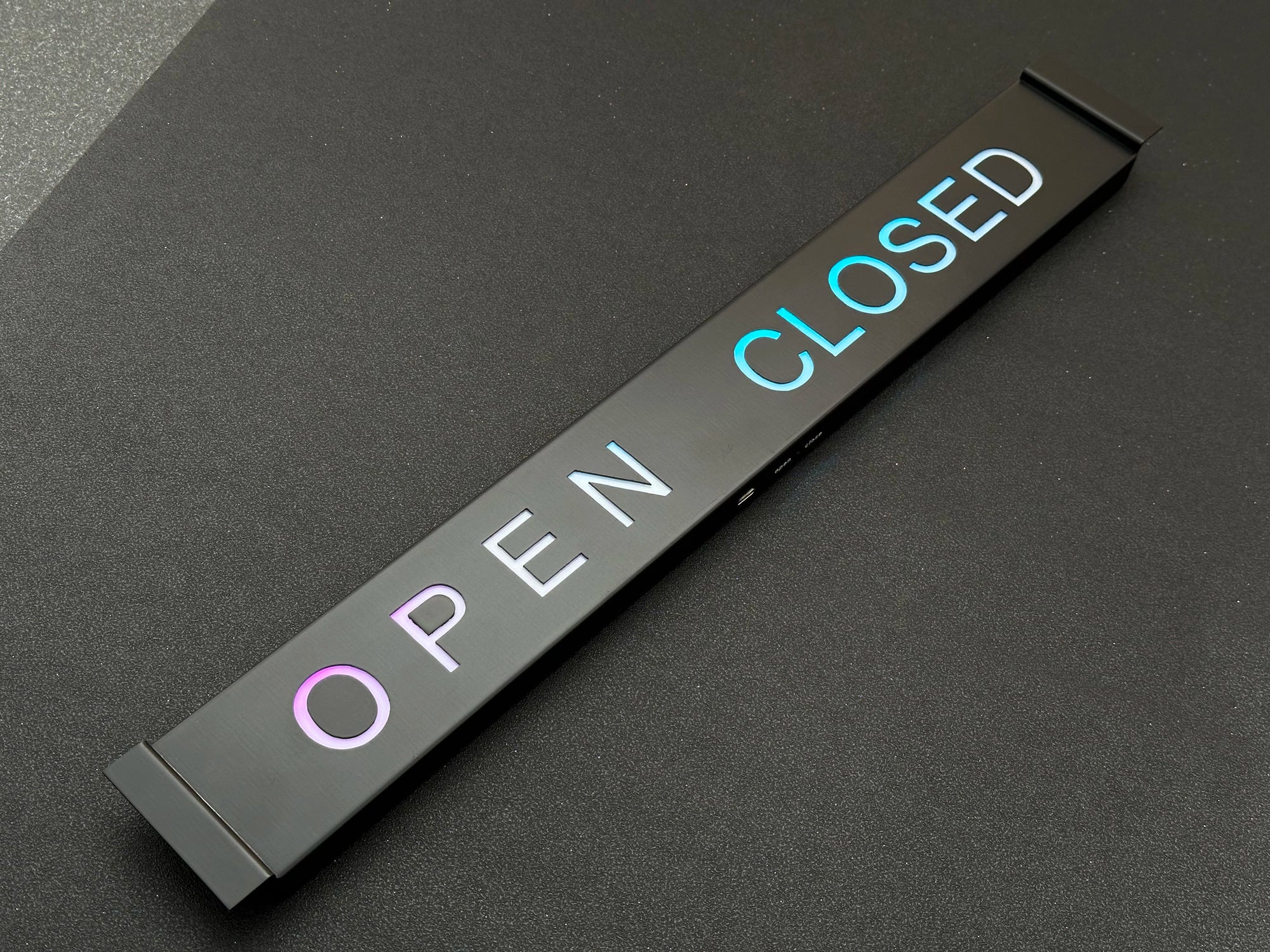 Rectangular 'Open' and 'Closed' sign on a dark surface