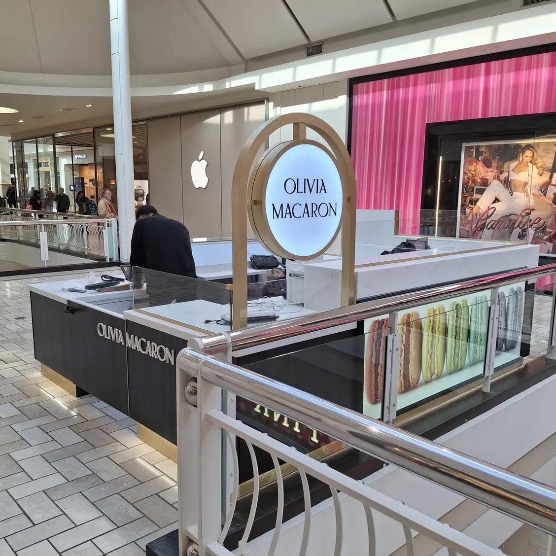 Custom retail kiosk counter featuring an illuminated oval business sign in a modern mall setting.