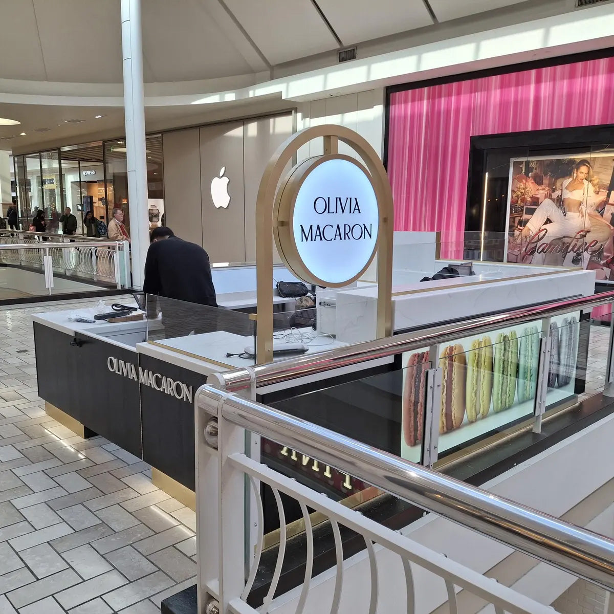 Custom retail kiosk counter featuring an illuminated oval business sign in a modern mall setting.