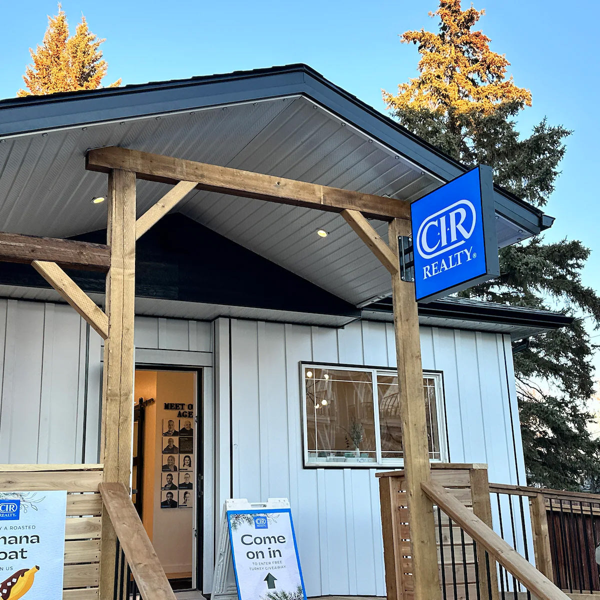Exterior blue projecting blade sign with white branding mounted on a rustic wooden beam of a commercial building.