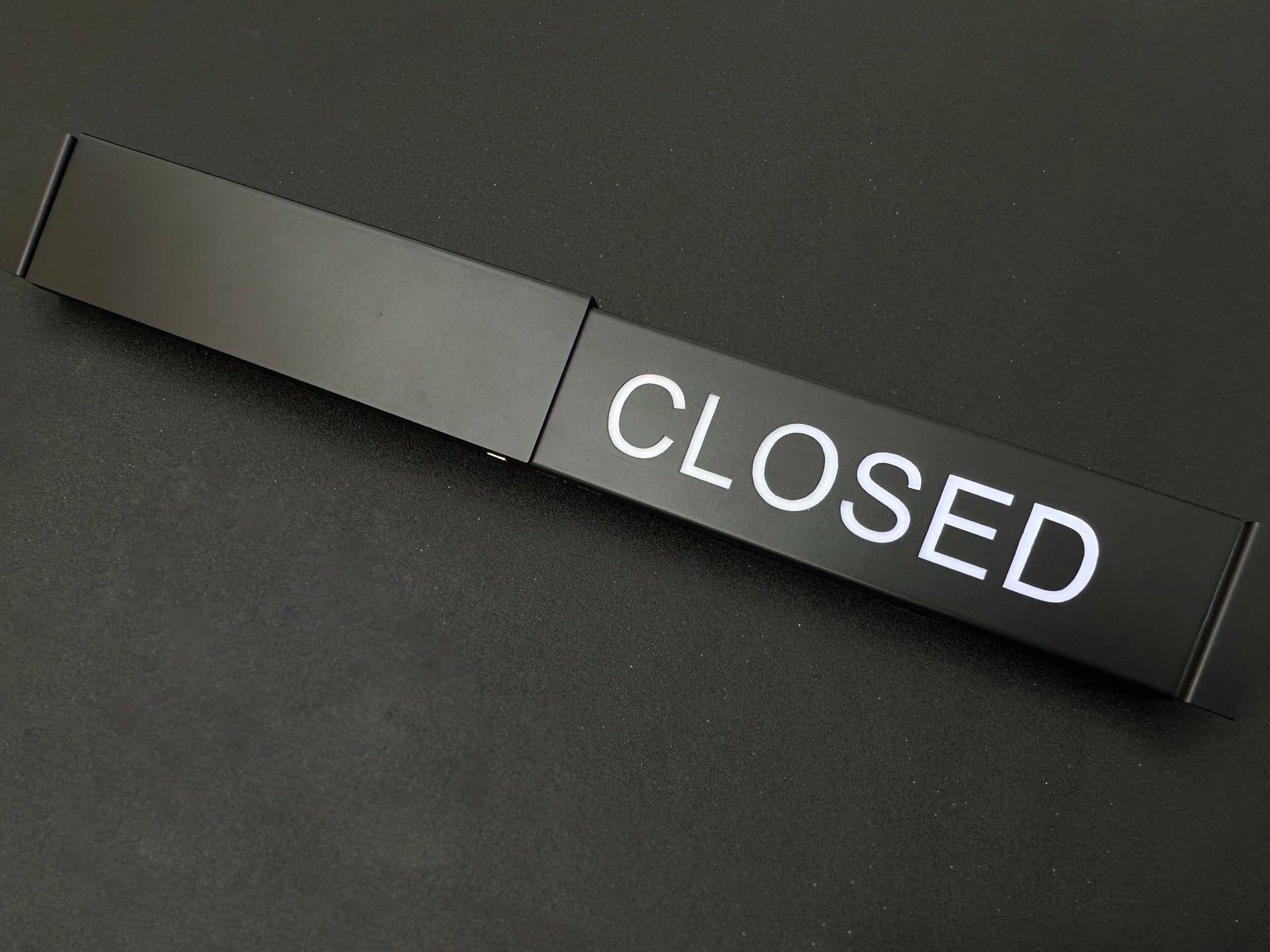 Black door handle with 'CLOSED' label on a black background