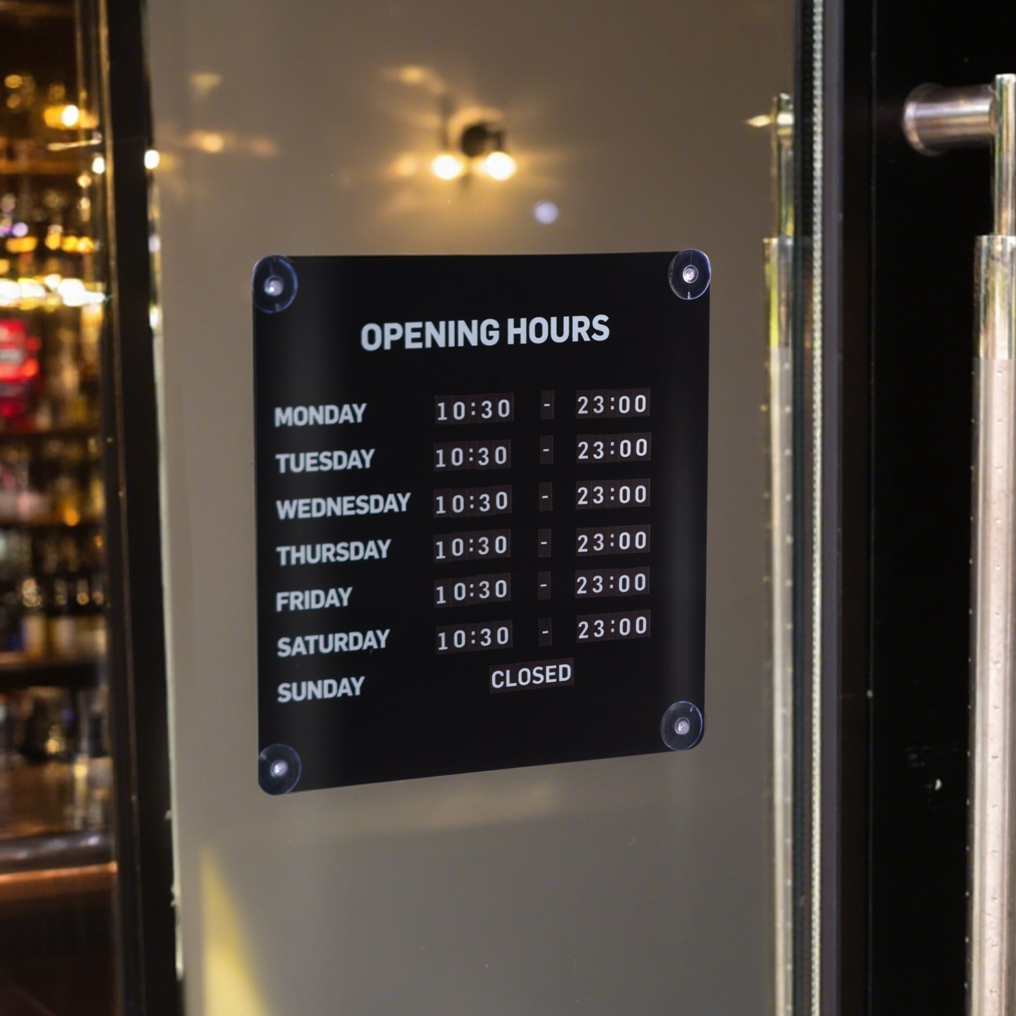 Opening hours sign on a door with a bar interior in the background