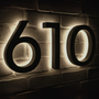 illuminated house numbers '610' on a brick wall