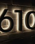  illuminated house numbers '610' on a brick wall