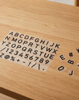 Sheet of black acrylic letter, number and symbol tiles for a changeable menu board on a wood table