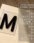 Close-up of a 2.36 inch black letter tile with the included letter, number and symbol counts