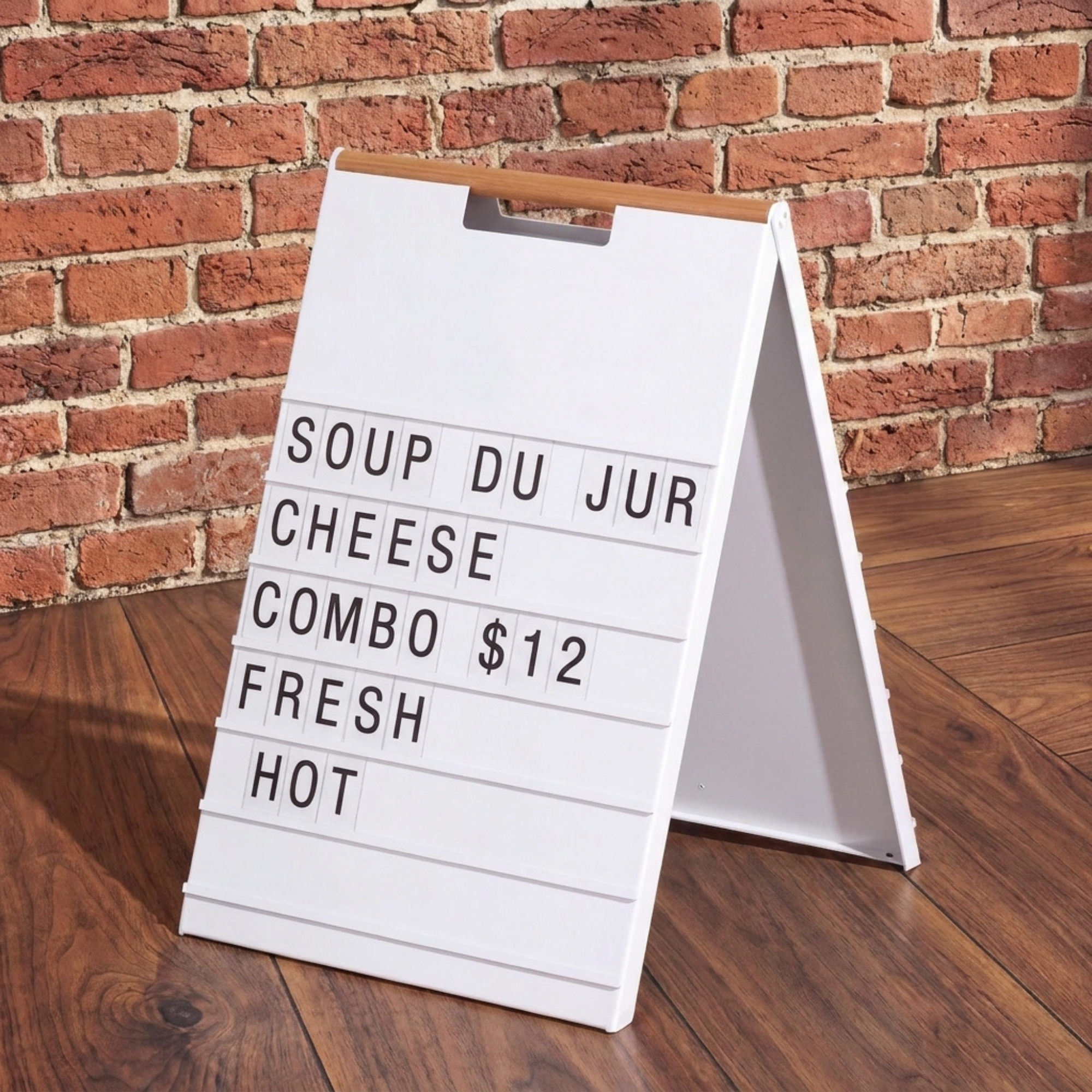 White A-frame menu board with a wood handle displaying a daily special menu against a brick wall