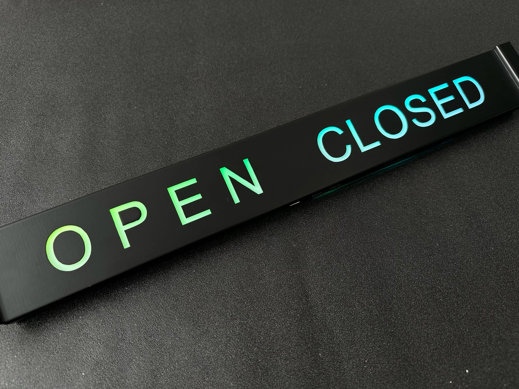 Open closed sign with green 'OPEN' and blue 'CLOSED' text on a black background