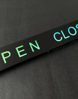 Open closed sign with green 'OPEN' and blue 'CLOSED' text on a black background