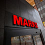 Illuminated 3D channel letter sign reading MARKET with red acrylic face and black sides