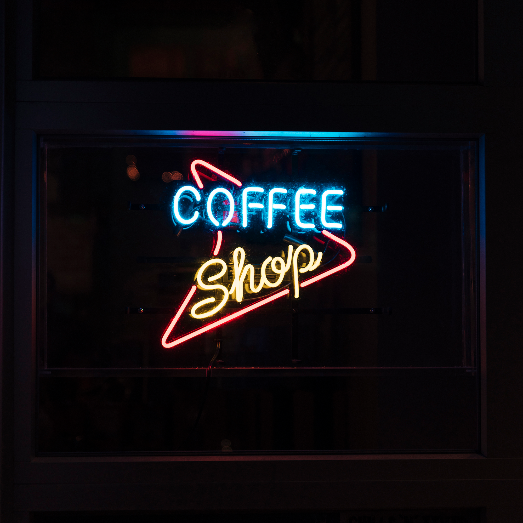 Custom LED neon coffee shop sign hanging in window for cafe branding