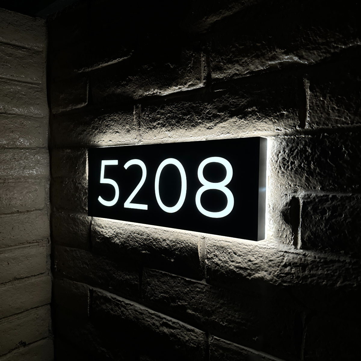 Illuminated house numbers glowing brightly at night for easy home identification
