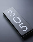 Rectangular metal sign with '305' on a dark background